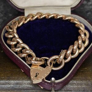 Heart-shaped padlock pendant on a chunky gold chain in a purple velvet jewelry box