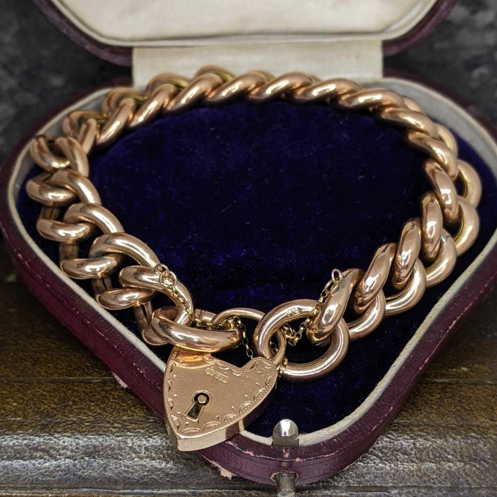 Heart-shaped padlock pendant on a chunky gold chain in a purple velvet jewelry box