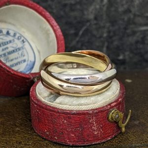 Gold wedding bands resting in a red velvet jewelry box, with the lid open