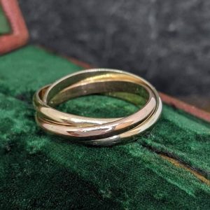 Two gold wedding rings resting together on green velvet, symbolizing commitment and union, close-up detail.