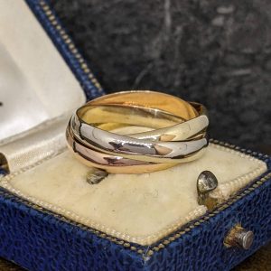Two-tone ring with overlapping yellow, white, and rose gold bands resting in a blue velvet jewelry box.