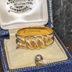 Gold twisted-rope style gold ring in a blue jewelry box, with maker's marks on the inner band.
