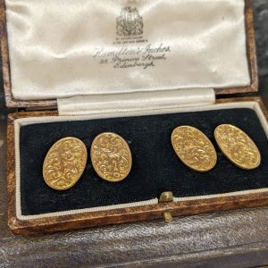 Vintage gold-tone oval cufflinks with intricate floral engraving in a satin-lined jewelry box, four pieces total.