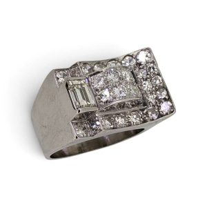 Diamond-studded wide metal ring with square cluster centerpiece and pavé diamonds on a brushed metal band reposed at an angle